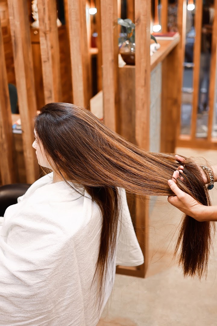 A stylist working through freshly treated lengths at the wood partition